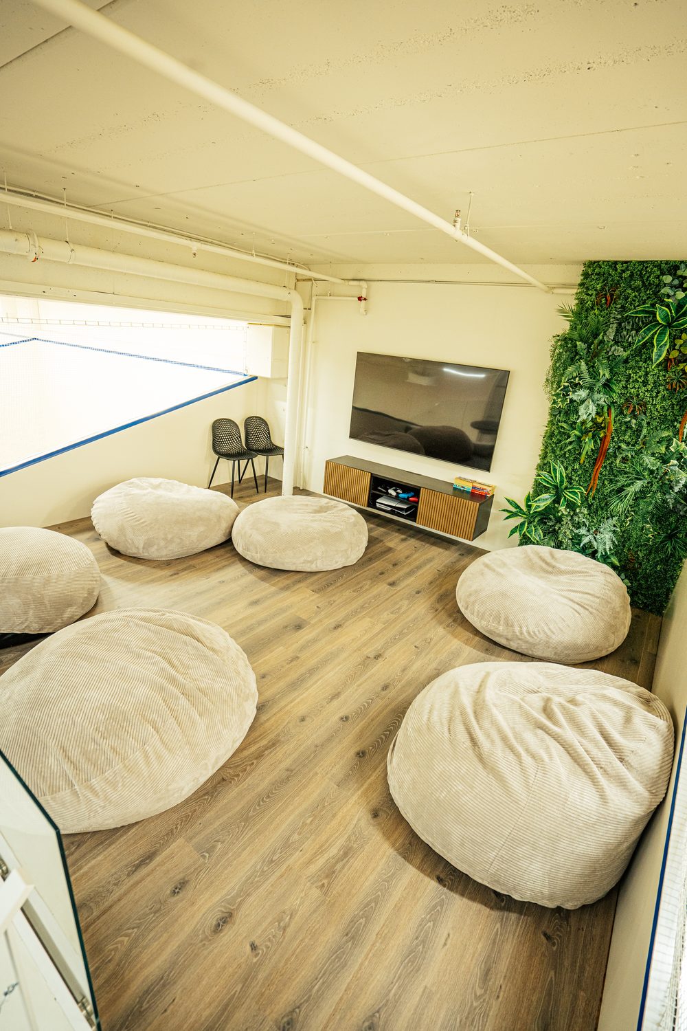 Relaxation room with bean bags, TV and green wall for players